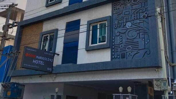 Un hotel de varios pisos con fachada moderna, que presenta un letrero llamativo del Hotel Marigold #2.
