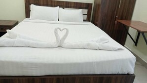 Una cama bien hecha con una toalla dispuesta en forma de corazón.