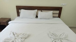 Una cama bien hecha con sábanas blancas y dos toallas dobladas en forma de flores.