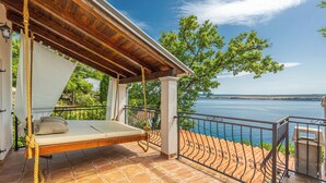 Eine Holzterrasse mit einer Hängematte, einem Geländer und Blick aufs Meer.