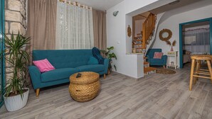 Ein Wohnzimmer mit einem blaugrünen Sofa, einem Korbwannenstuhl und einer Topfpflanze.