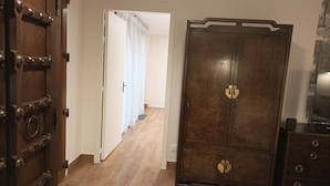 A room with a wooden wardrobe, a door with metal studs, and a wooden floor.