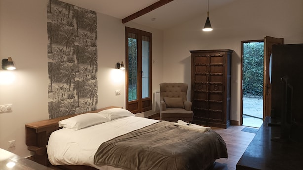 A bedroom with a bed, a chair, a wardrobe, and a view of the outdoors.