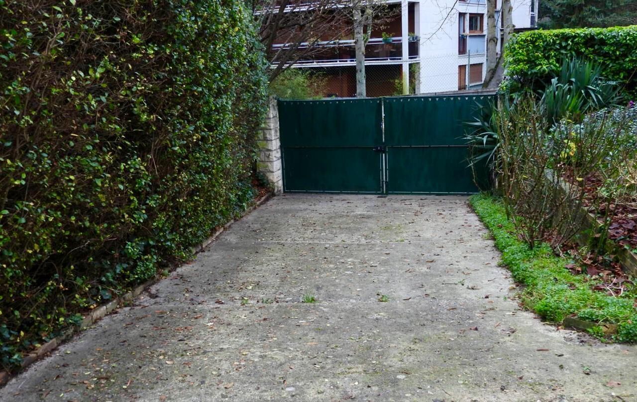 Een hek afsluit de ingang, met een betonnen pad dat naar een gebouw leidt.