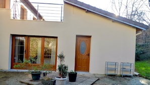 A building with a wooden door, a window with a curtain, and potted plants in front.