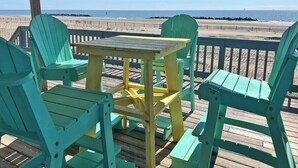 A wooden deck with a table and chairs, overlooking a beach. - Pompano - Beachfront - Island Realty (Grand Isle)