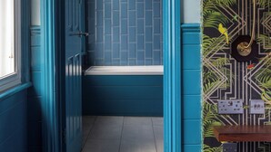 A hallway with a blue door leading to a bathroom with a tiled wall. - The Ship Rooms (London)