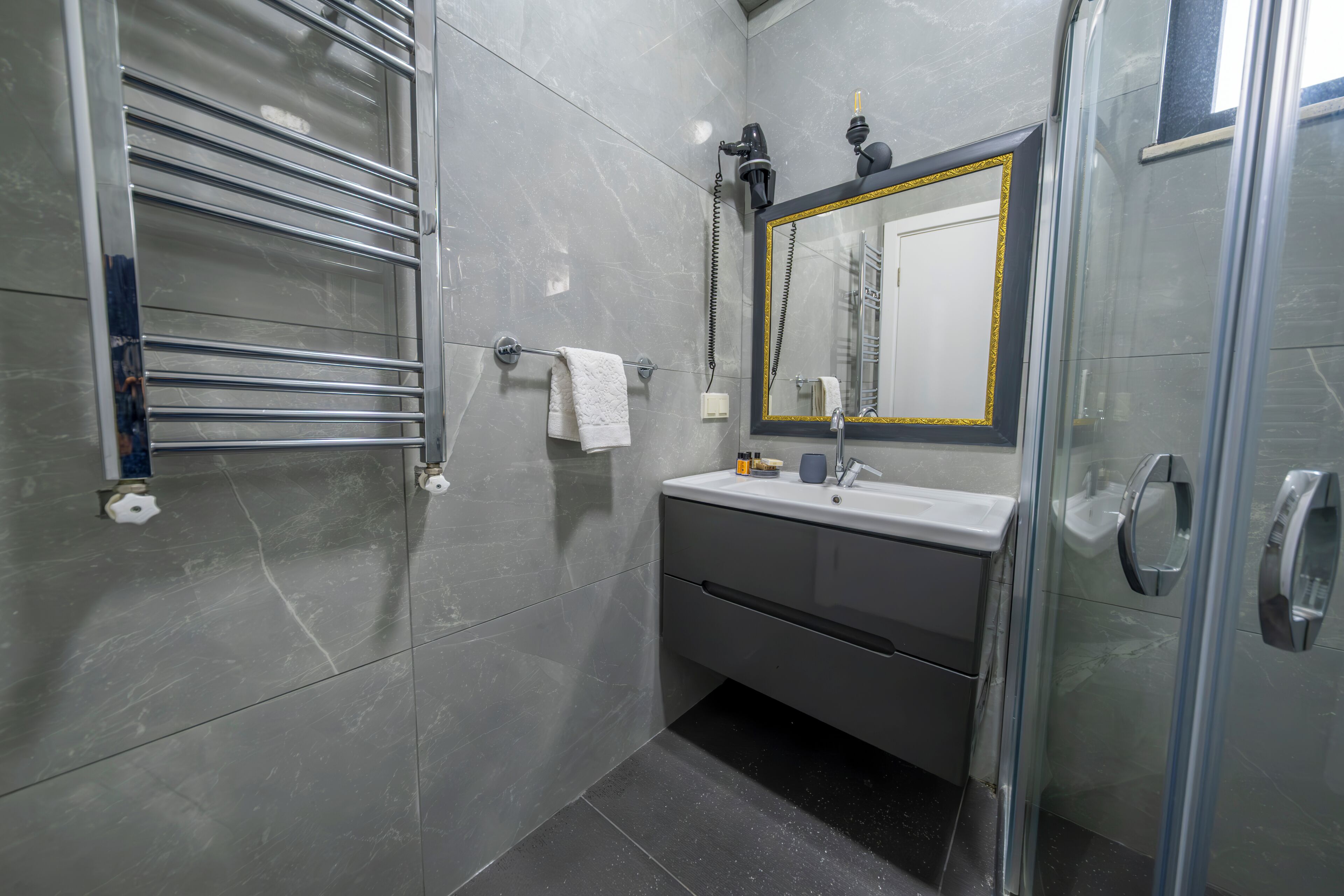 A modern bathroom with a glass shower enclosure, a vanity with a mirror, and a towel rack.