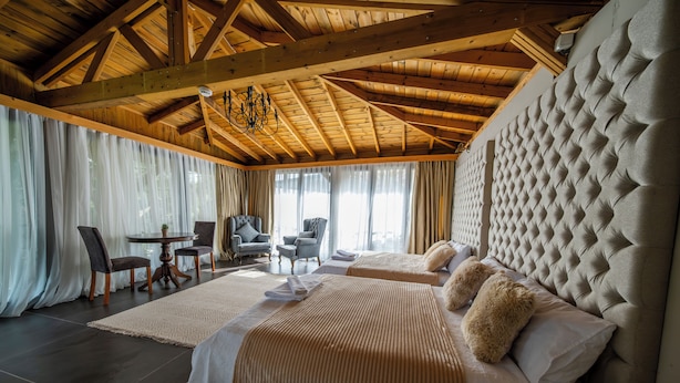 A spacious bedroom with a large bed, a wooden ceiling, and a view of the outdoors. - Assosa Country House (Ayvacik)