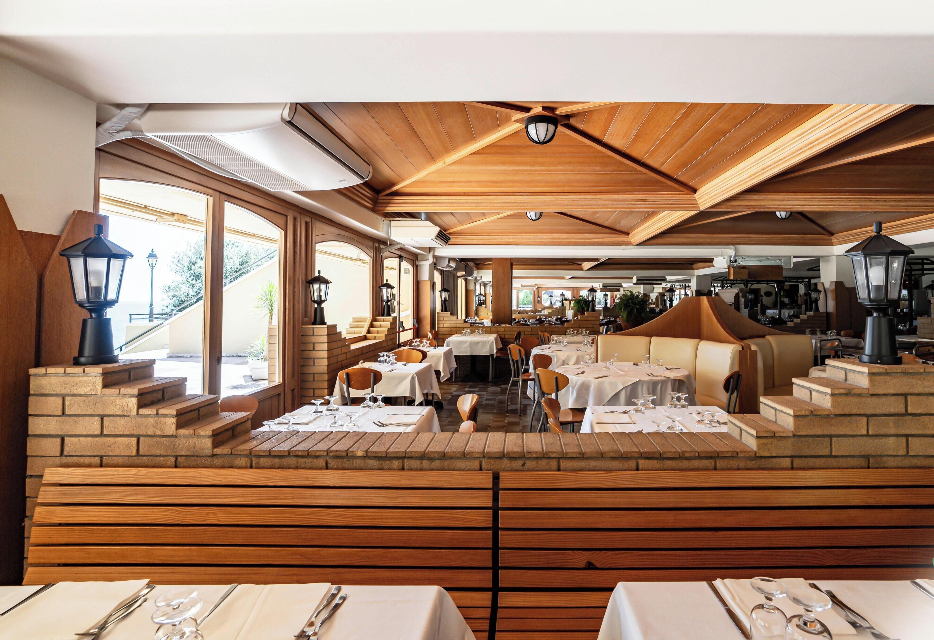 Un restaurante con vigas de madera en el techo, paredes de ladrillo y mesas dispuestas para comer.