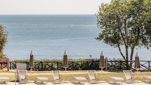 A poolside area with lounge chairs and umbrellas, overlooking a body of water. - Hotiday Apartment Collection-Pugnochiuso (Vieste)