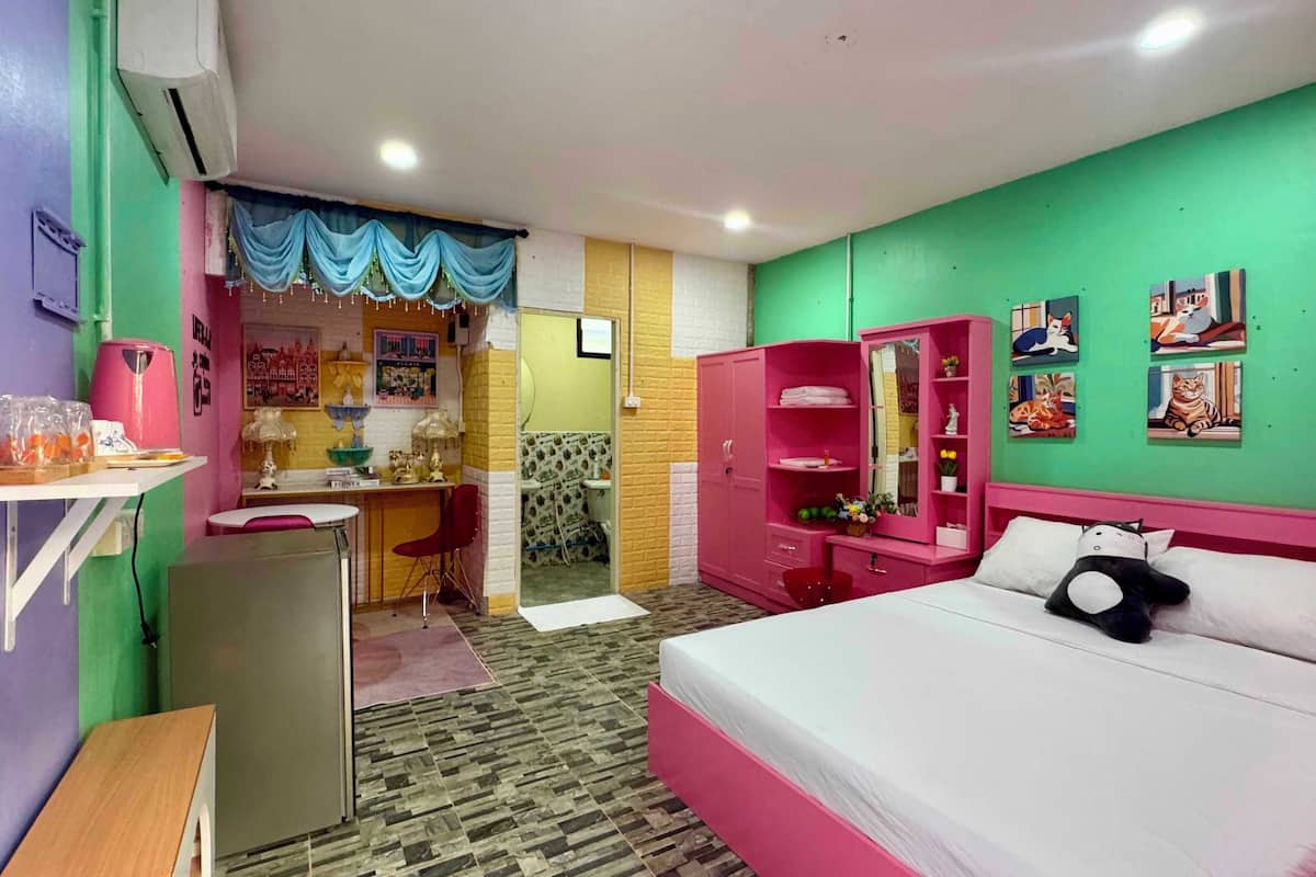 A room with a bed, a desk, a chair, a wardrobe, and a bathroom.