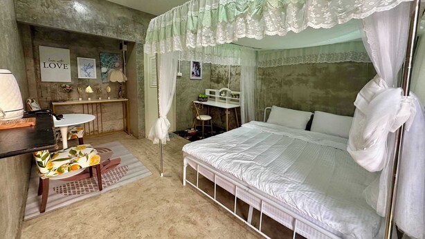 A bedroom with a bed, bedside table, and a desk with a chair. - OYO 75539 Phanthida Resort and Cafe (Pranburi)
