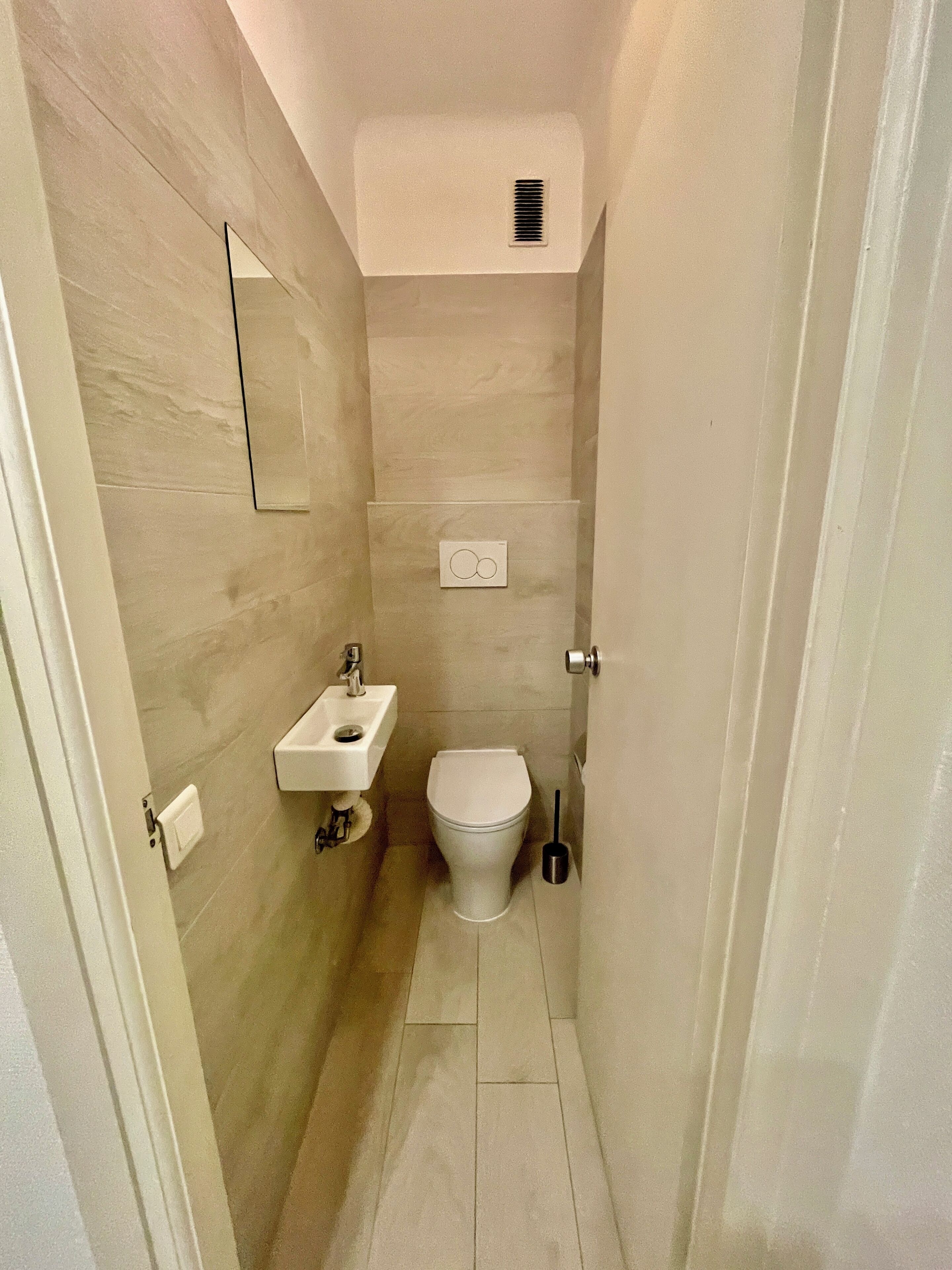 Un baño pequeño con inodoro, lavamanos y espejo.