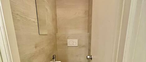 Un baño pequeño con inodoro, lavamanos y espejo.