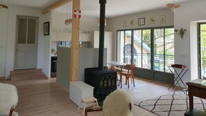 A cozy living room with a fireplace, wooden beams, a dining area, and a view through large windows. - Merry Méry (Mery)