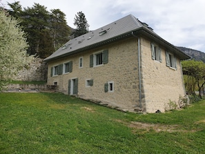 A stone building with a sloped roof, multiple windows with shutters, and a grassy foreground. - Merry Méry (Mery)
