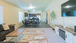 Un salon moderne avec un canapé, une table basse et un téléviseur à écran plat fixé au mur.