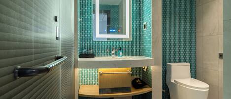 A modern bathroom with a glass partition, a sink with a mirror, and a toilet.