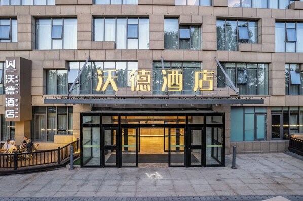 A hotel entrance with a modern facade, glass doors, and a sign in a foreign language. - World Hotel Weihai Bathing Beach (Weihai)