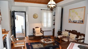 A cozy living room with wooden furniture, a round coffee table, and a map on the wall. - Traditional island house (Andros)