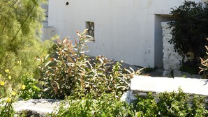 A white building with balconies, a blue door, and a window with a shutter. - Traditional island house (Andros)