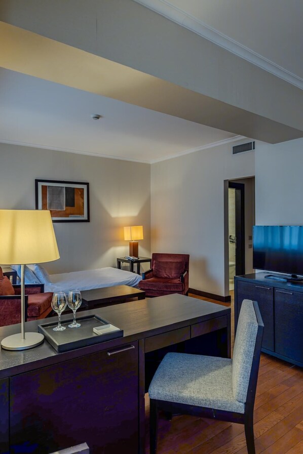 A hotel room with a bed, a desk with a chair, a TV, a lamp, and a framed picture on the wall. - Hotel Rivo Timisoara (Timisoara)