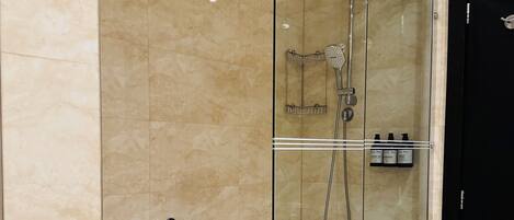 A modern bathroom with a glass-enclosed shower, a white bathtub, and a black door.