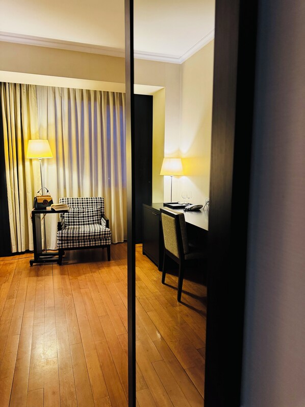 A hotel room with a checkered armchair, a desk with a lamp, and a bookshelf. - Hotel Rivo Timisoara (Timisoara)
