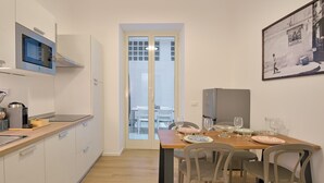 A modern kitchen with a dining area, a refrigerator, and a microwave. - Palazzo Gregorietti Boutique Apartments (Palermo)
