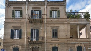 A multi-story building with balconies, a central entrance, and a street view with parked cars. - Palazzo Gregorietti Boutique Apartments (Palermo)
