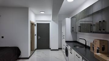 Una cocina moderna con piso de mármol, lavadora y pileta.