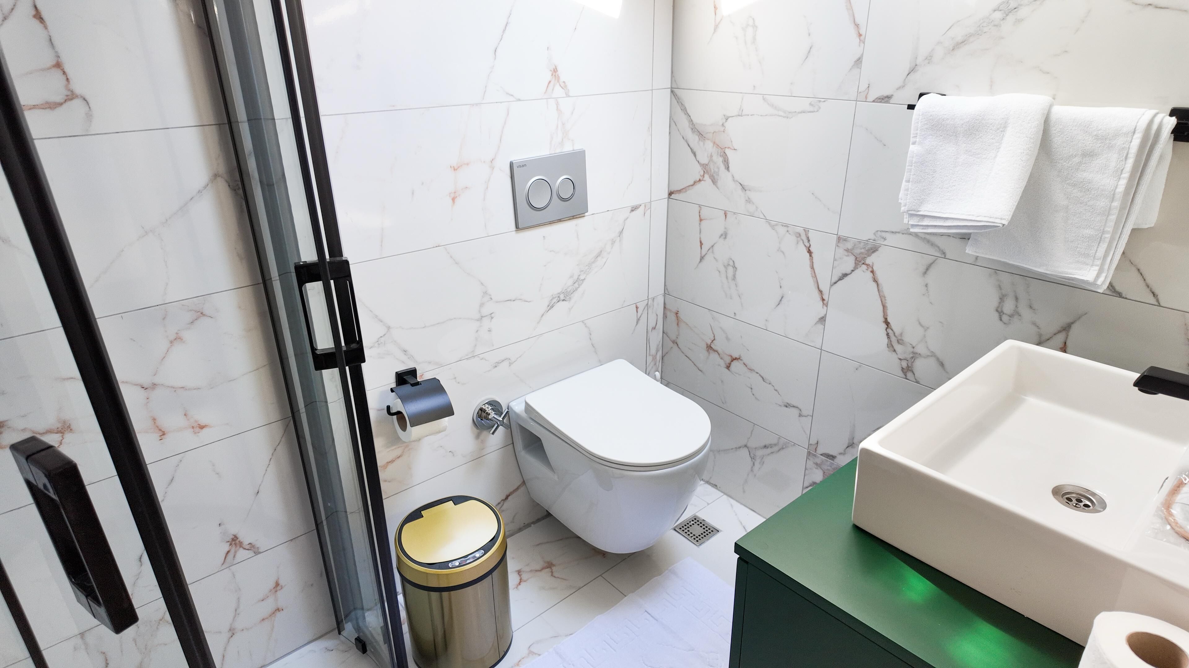 A bathroom with a toilet, sink, and shower area.