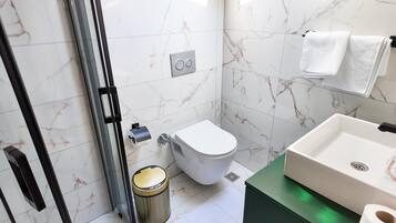 A bathroom with a toilet, sink, and shower area.