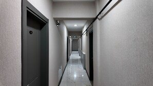 A narrow, well-lit hallway with a tiled floor, leading to a door marked with the number 105. - Faraza Rooms (Serdivan)
