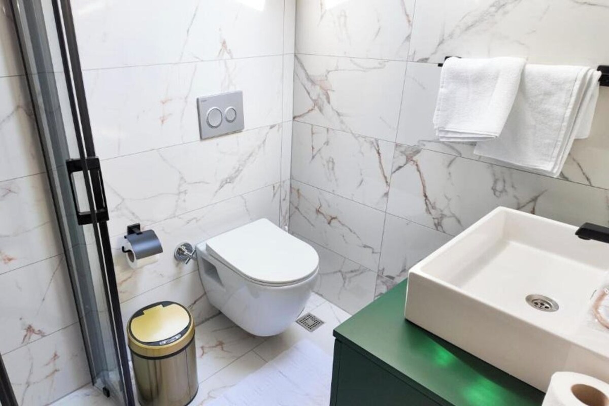 A bathroom with a toilet, sink, and trash can.