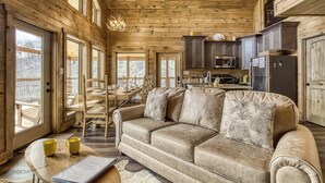 A cozy cabin interior with a wooden ceiling, a sofa with cushions, a dining table, and a kitchen area. - Smoky Mountain Dreamin'-Mountain Views, Hot Tub, $560 tickets each paid day! (Sevierville)