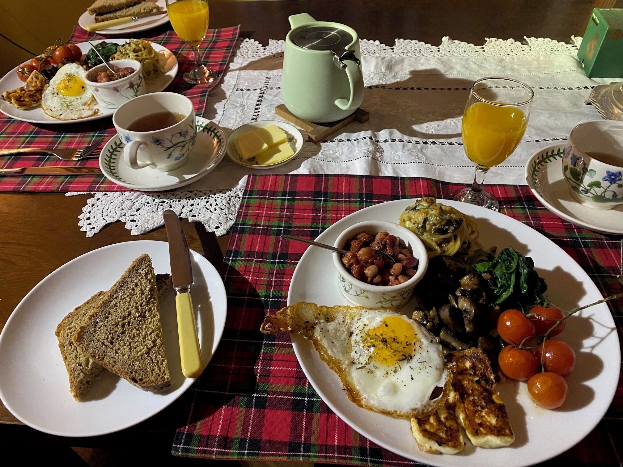 Una mesa de desayuno con diferentes platillos, como tostadas, huevos, tomates y una taza de té.