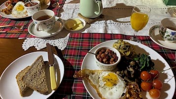 Una mesa de desayuno con diferentes platillos, como tostadas, huevos, tomates y una taza de té.