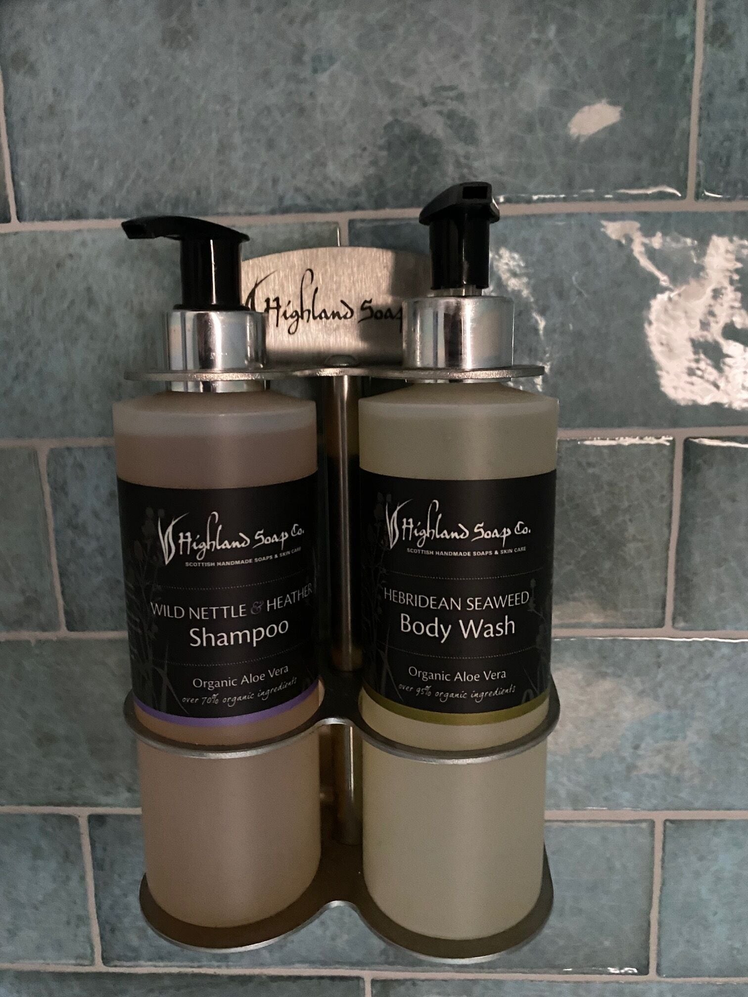 Two bottles of Highland Soap Co. shampoo and body wash with pumps, placed on a tiled surface.