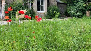 Une maison en pierre avec un jardin à l’avant.