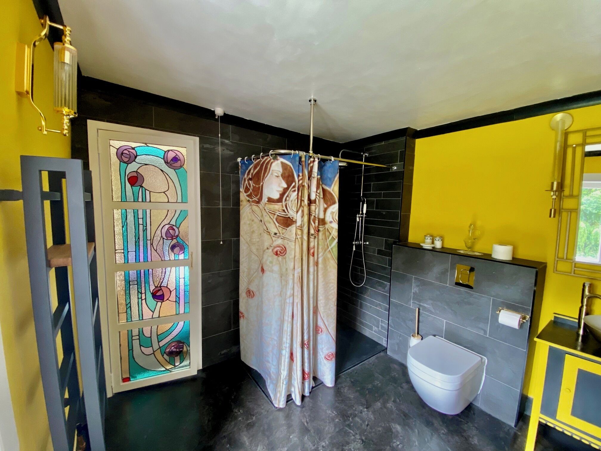 Une salle de bain équipée d’une douche, de toilettes, d’un lavabo et d’un vitrail décoratif.
