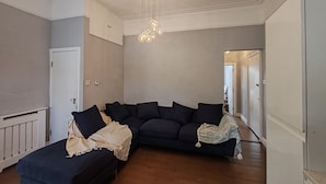 Un salon avec un canapé de couleur sombre, une porte blanche et un plancher en bois.
