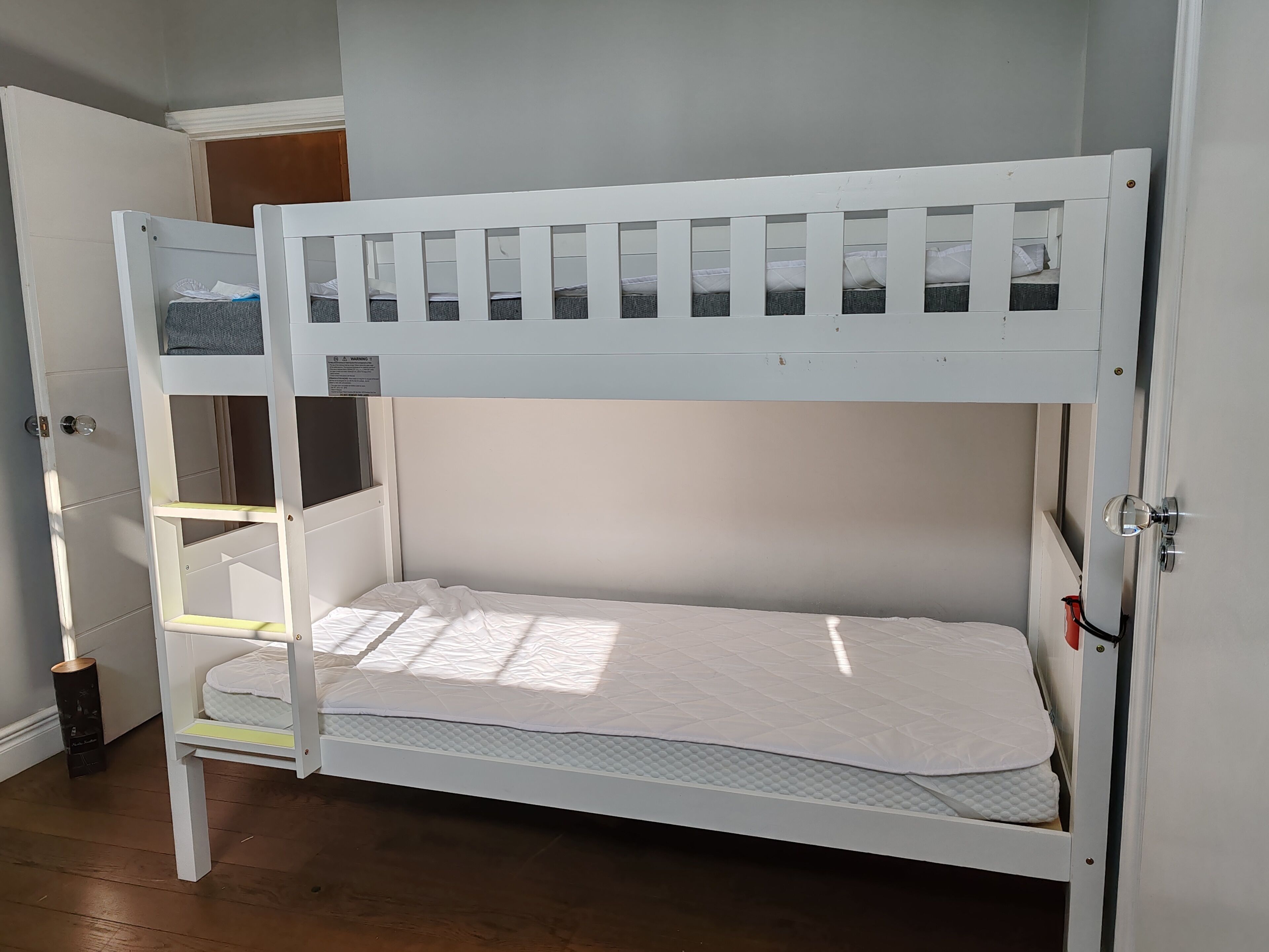 Un lit superposé composé d’un lit inférieur et d’un lit supérieur, tous deux dotés de draps blancs.