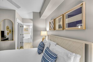 Habitación de hotel con una cama grande, un espejo, dos cuadros enmarcados y una lámpara.