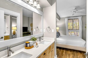 Un baño moderno con un espejo grande, lavamanos dobles y un mueble de tocador con espacio de almacenamiento.