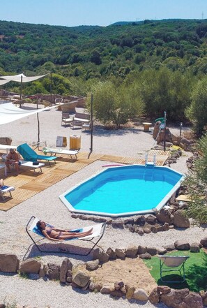 A pool area with lounge chairs, a small pool, and a view of a hilly landscape. - Pasare Glamping (Perfugas)