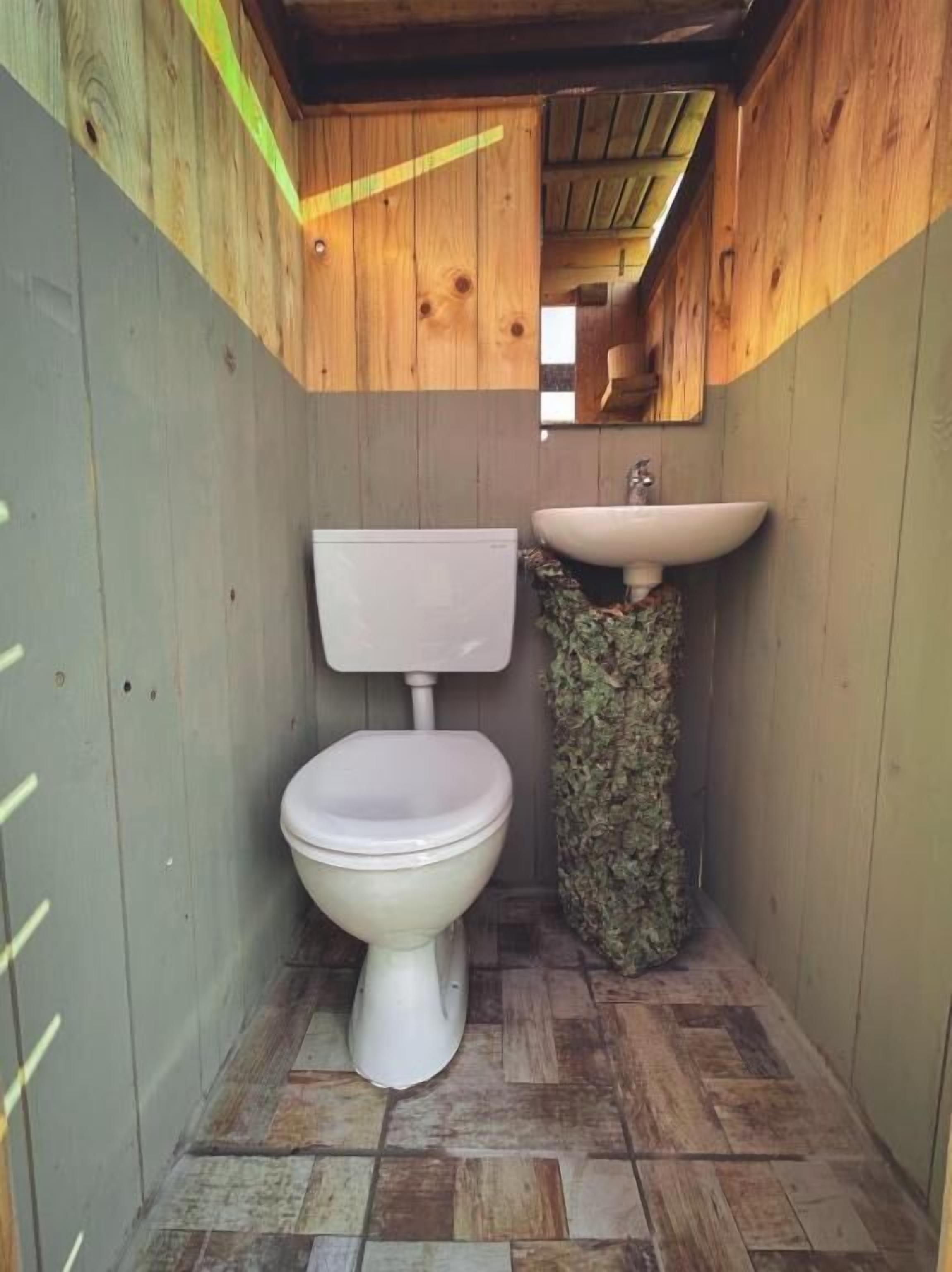 A small, wooden-paneled bathroom with a toilet and a sink.