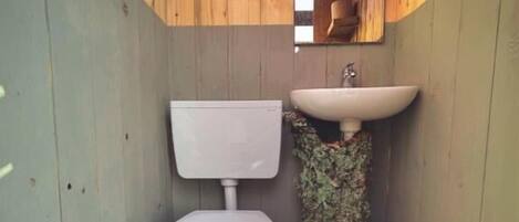 A small, wooden-paneled bathroom with a toilet and a sink.