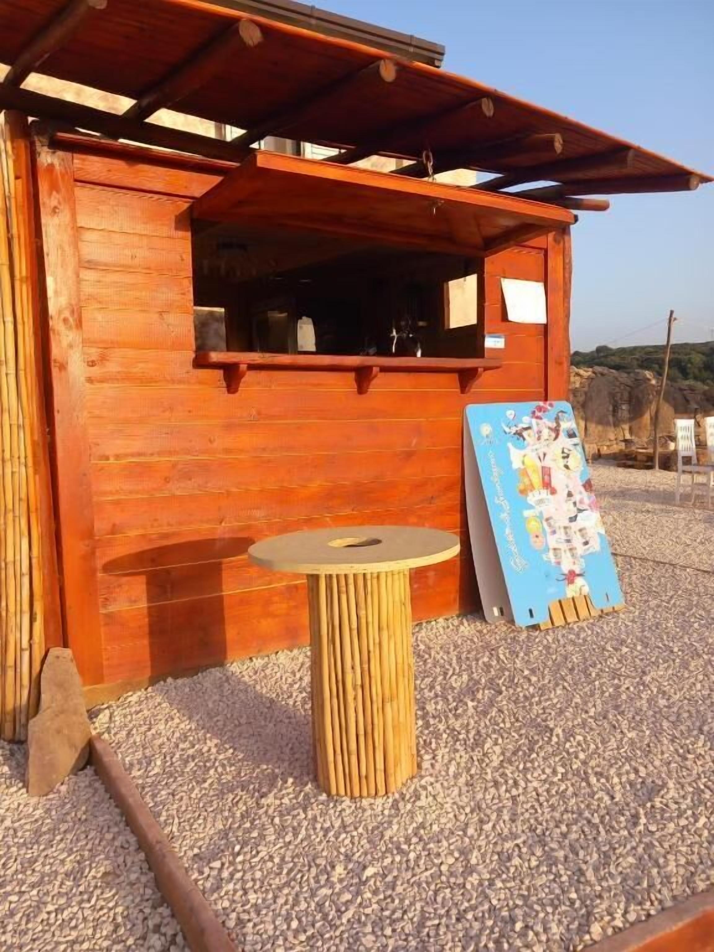A wooden building with a covered outdoor seating area, a small table, and a poster.